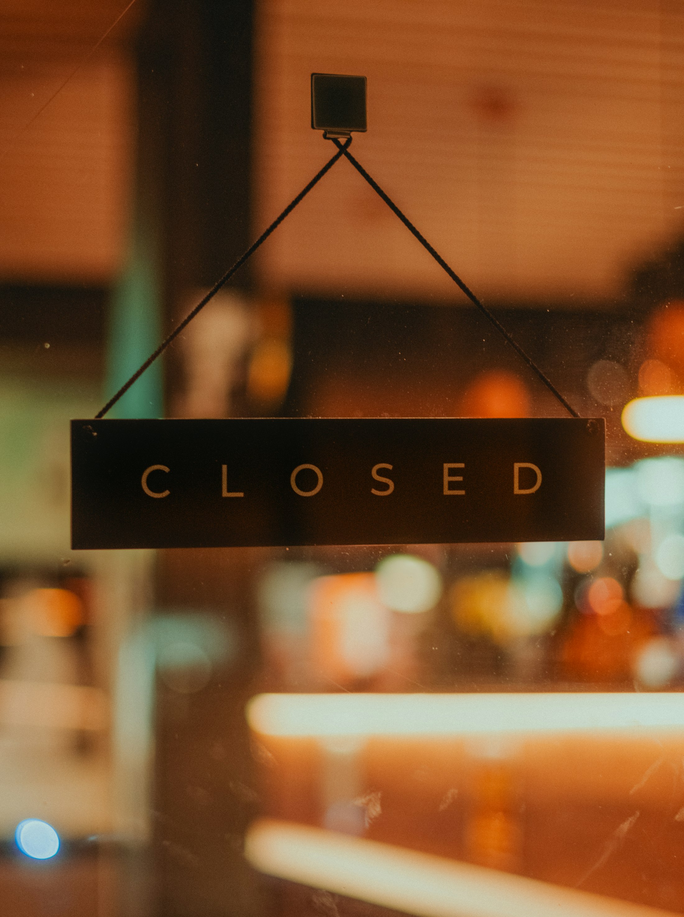 A Closed sign hanging in a shop door at night