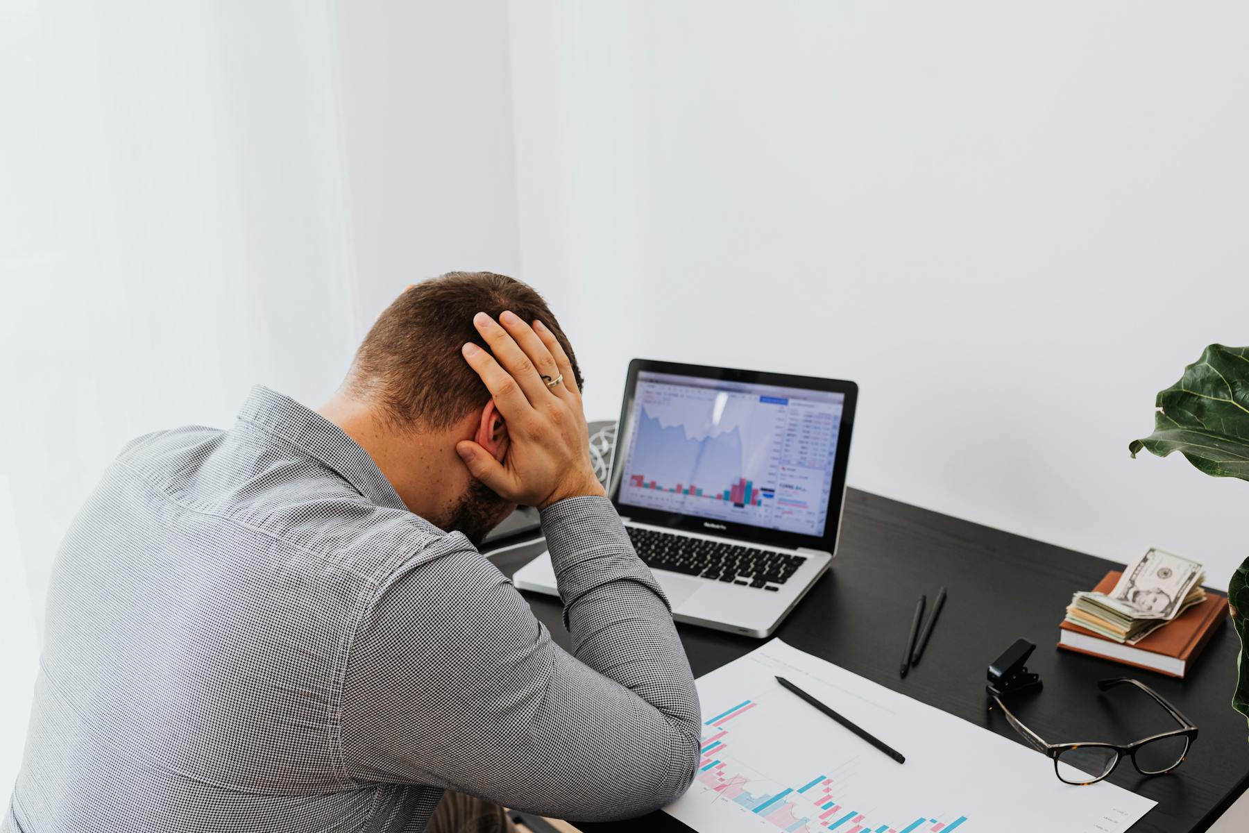 A frustrated business owner holding their head while looking at a laptop
